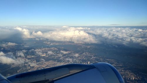 Aerial view of aircraft wing over landscape against sky