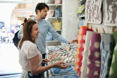 Smiling owner showing fabric swatches to male customer at shop