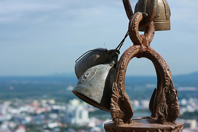 Close-up of rusty bells hanging against sky
