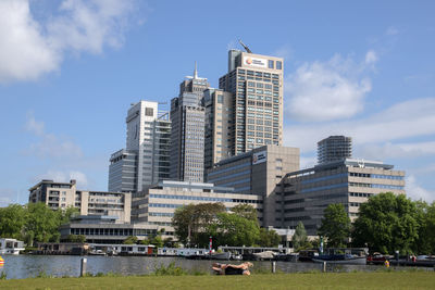 Buildings by river against sky in city