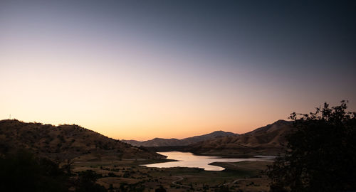 Scenic view of silhouette mountains against clear sky during sunset