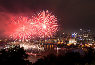 Firework display over illuminated buildings in city at night