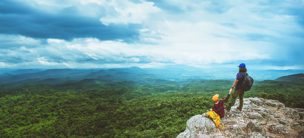 Rear view of man standing on mountain against sky