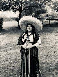 Portrait of woman wearing hat while standing against trees