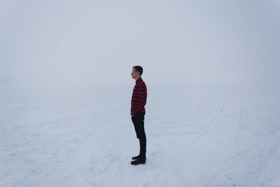 Side view of man standing on snow covered field
