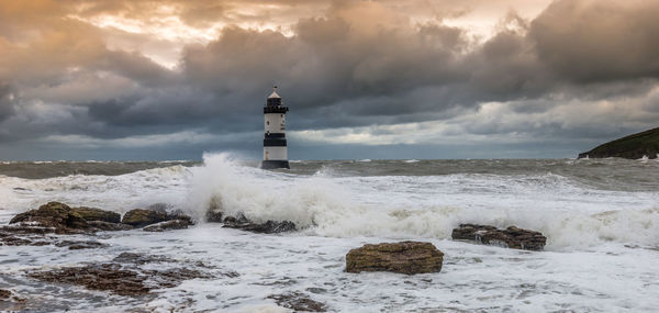 Lighthouse by sea against sky