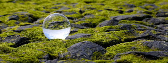 Close-up of crystal ball on rock by water