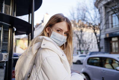 Portrait of young woman standing in city