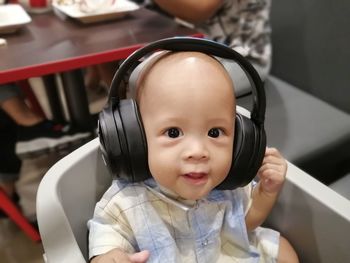 Portrait of cute baby boy listening to music at home