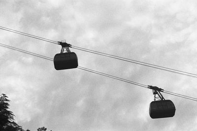 Low angle view of overhead cable cars against sky