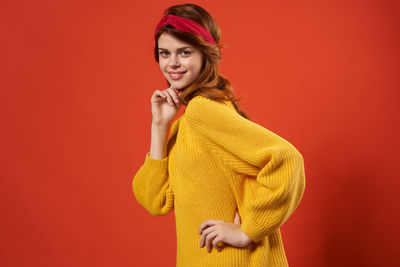 Portrait of smiling young woman against red background