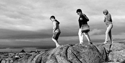 People walking on rock against sky