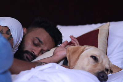 Portrait of dog lying on bed with human