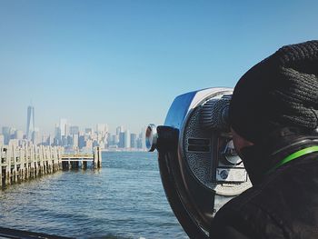 Rear view of man looking at one world trade center through coin-operated binoculars