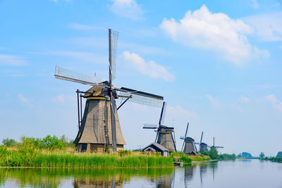 Traditional windmill by lake against sky