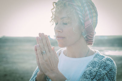 Woman with hands clasped standing outdoors