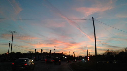 Cars on road against sky during sunset