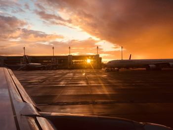 Airplane on runway against sky during sunset