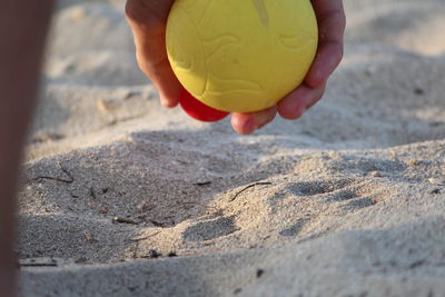 Midsection of person holding umbrella on sand
