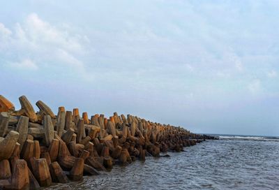 Stack of groyne in sea against sky