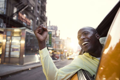 Cheerful man peeking from taxi during sunset