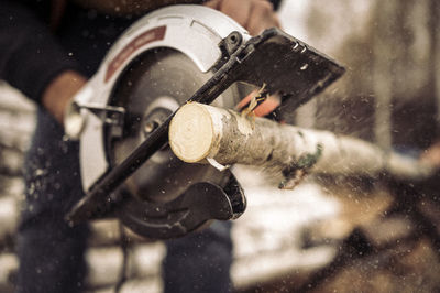 Hands of man sawing wood log