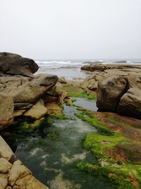 Rocks in sea against clear sky