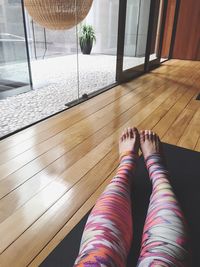 Low section of woman wearing leggings while sitting on exercise mat at home