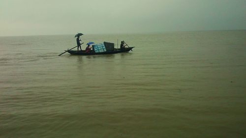 Men fishing in boat against sky