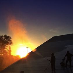 Silhouette of people on landscape at sunset