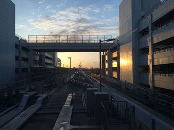 Railroad tracks amidst buildings against sky during sunset