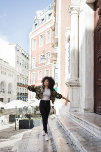 Happy woman with arms outstretched walking on staircase