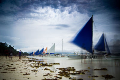 Sailboats on beach against sky