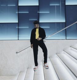 Full length of young man looking down standing on staircase