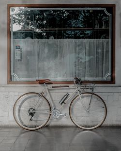 Bicycle parked on footpath against building