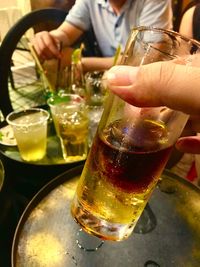 Cropped image of hand holding beer glass on table