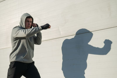 Side view of man standing against wall