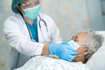 Doctor wearing flu mask examining senior woman at hospital