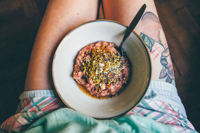 Low section of person with bowl of porridge on lap