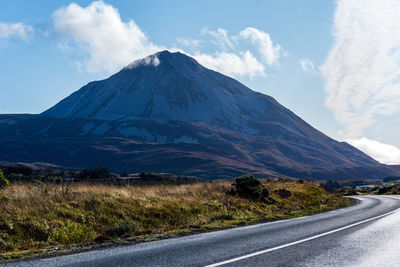 Road by mountains against sky