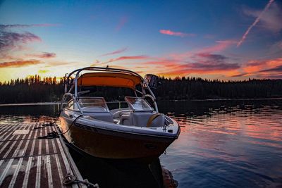 Boat moored in lake against sky during sunset