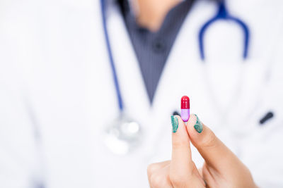 Close-up midsection of female doctor holding capsule 