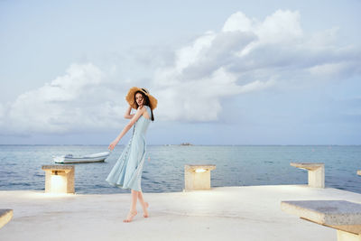 Woman standing at beach against sky