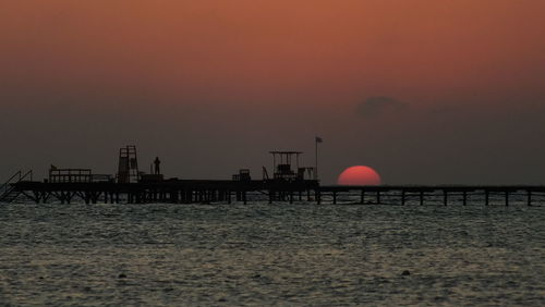 Silhouette pier over sea against sky during sunset