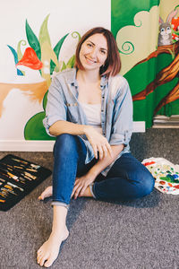 Smiling woman sitting against painted wall