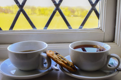 Close-up of coffee and snack by window