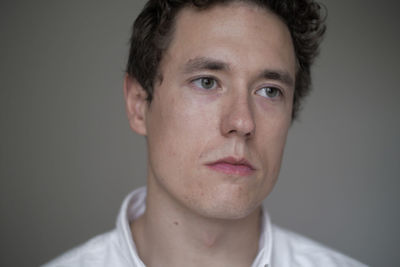 Close-up of serious young man against gray background