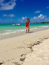 Rear view of woman on beach against sky