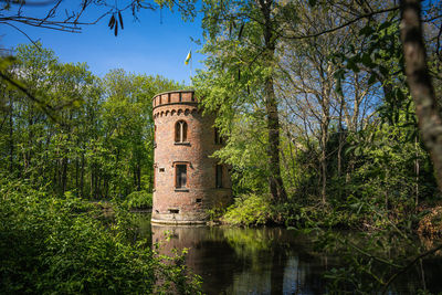 Built structure by plants in lake against sky