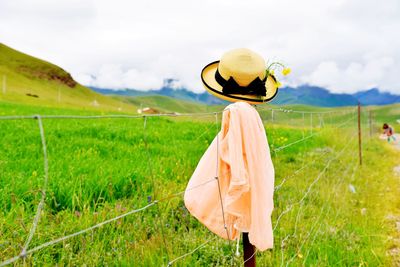 Scarf and hat on fence against cloudy sky